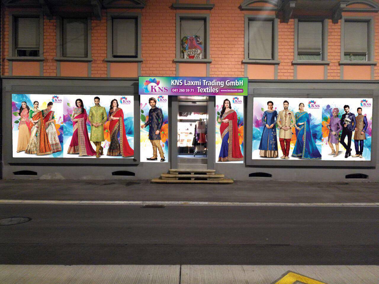 Schaufenster von KNS Laxmi Trading in Luzern mit Saree-Motiven am Abend beleuchtet