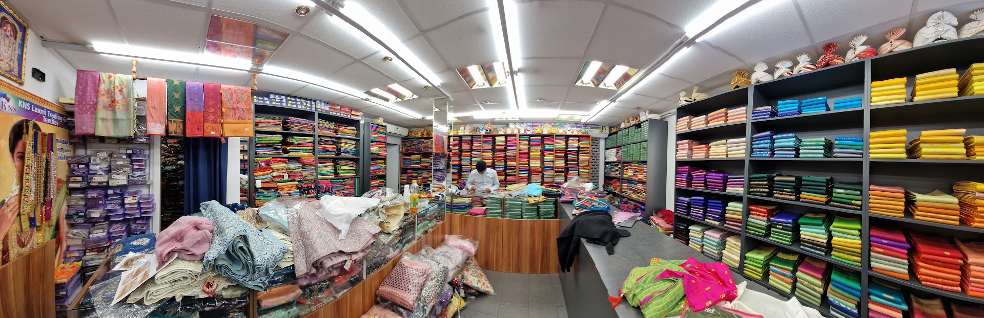Innenraum von KNS Laxmi Trading in Luzern mit Regalen voller farbiger Stoffe und Sarees